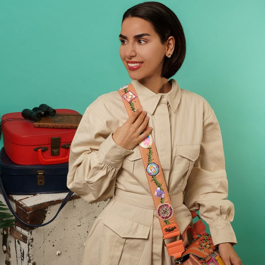 Woman holding a colorful bag strap with vintage suitcases in the background