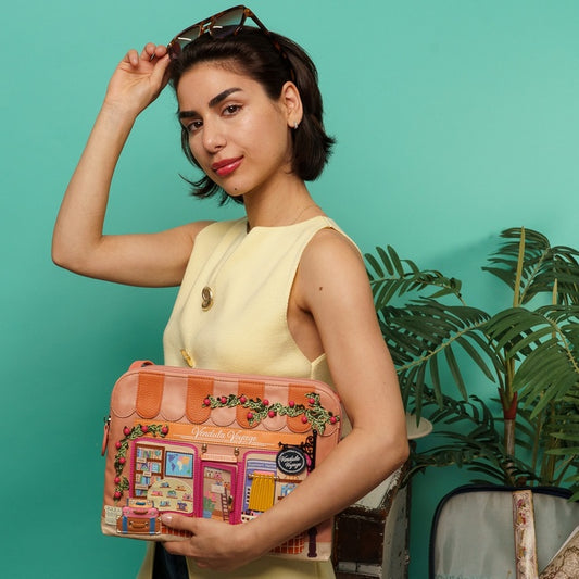 Woman holding a colorful handbag with a building design against a teal background