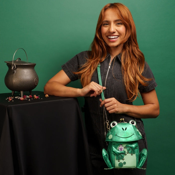 Woman holding a green frog-shaped bag against a green background