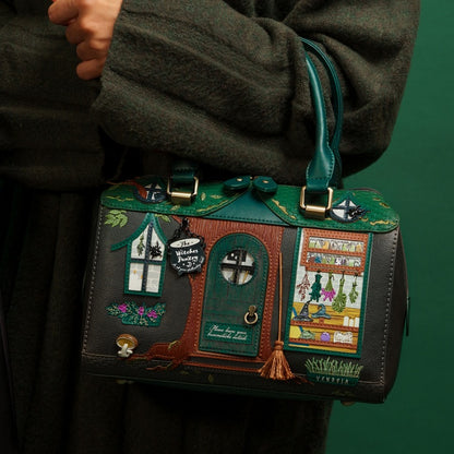 Handbag designed like a fairy house held by a person against a green background