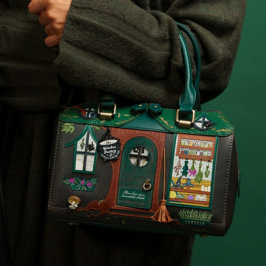 Handbag designed like a fairy house held by a person against a green background