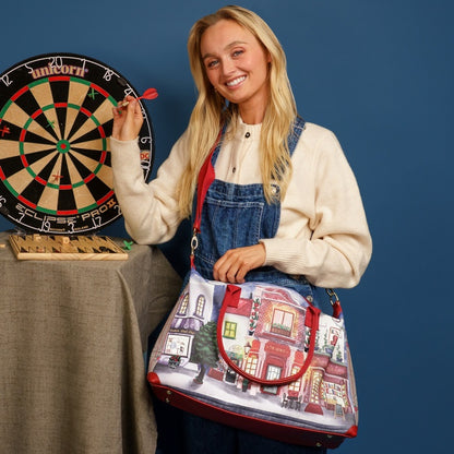 Woman holding a colorful bag with a building design, standing next to a dartboard.