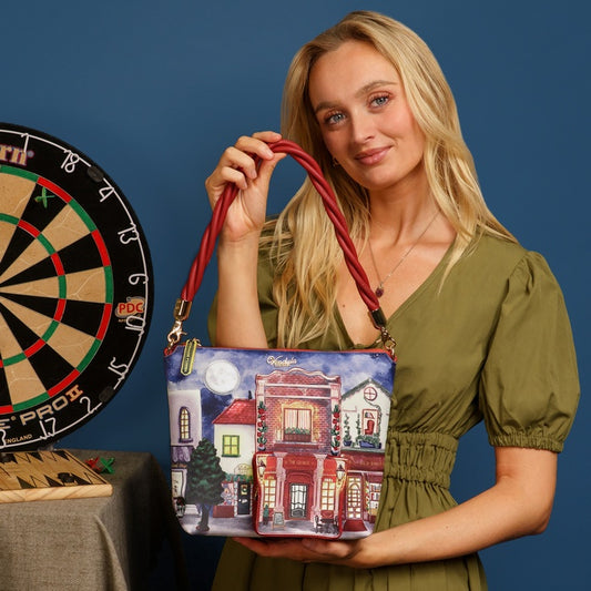 Woman holding a handbag with a house design next to a dartboard on a blue background