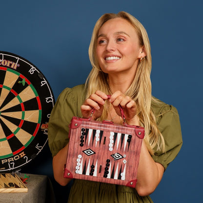 Woman holding a backgammon set with a dartboard in the background
