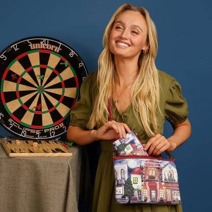 Woman holding a colorful bag with a building design next to a dartboard on a blue background
