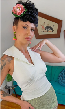 Woman with a floral headpiece posing in a room with a teal couch and framed pictures on the wall.