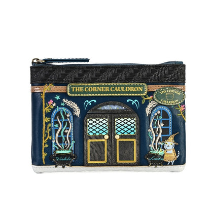 A small zip pouch designed to look like the character shop 'The Corner Cauldron' from The Chronicles of Narnia, featuring a navy blue facade with gold, green, and light blue details, set against a plain white background.