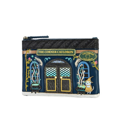 A small zip pouch designed to look like the 'The Corner Cauldron' shop facade from Harry Potter, featuring embroidered details, a cat character, and a dark woven top section, shown on a plain white background.