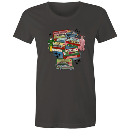 A graphic print on a light beige fabric featuring retro cassette tapes labeled 'Home Alone', 'Elf', 'The Grinch', 'National Lampoons Christmas', and 'A Christmas Story', with illustrated characters and black starbursts.