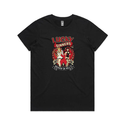 A black graphic t-shirt featuring a retro-style tattoo-style illustration of two pin-up girls, one angel and one devil, with the text 'LUCKY SINNERS' and 'HEAVEN OR HELL?'.