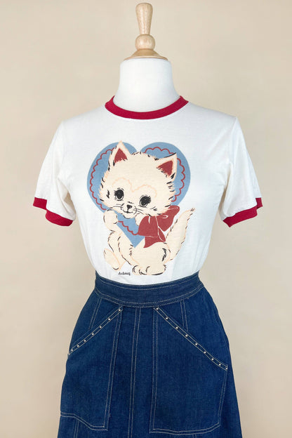 White t-shirt with a cat graphic on a mannequin against a beige background