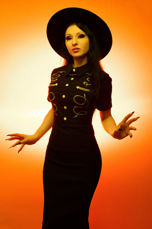 Woman in a black dress with gold accents against an orange background