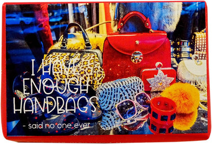 A square graphic print or card featuring a colorful collage of handbags, sunglasses, and accessories, with the text 'I HATE ENOUGH HANDBAGS - said no one ever' in white lettering.