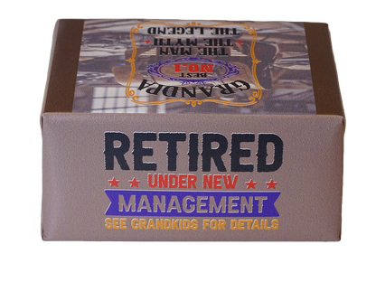 A rectangular product box with a brown and gray design, featuring the text 'RETIRED UNDER NEW MANAGEMENT' and 'SEE GRANDKIDS FOR DETAILS' on a white background.