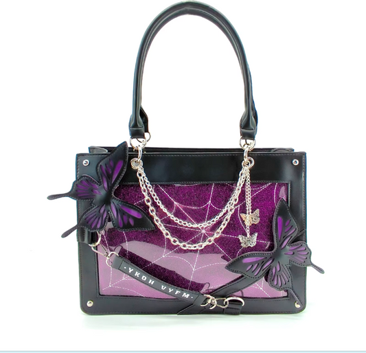 Black leather handbag with a purple glitter spiderweb pattern panel, black butterfly appliqués, silver chain details, and a black shoulder strap on a white background.