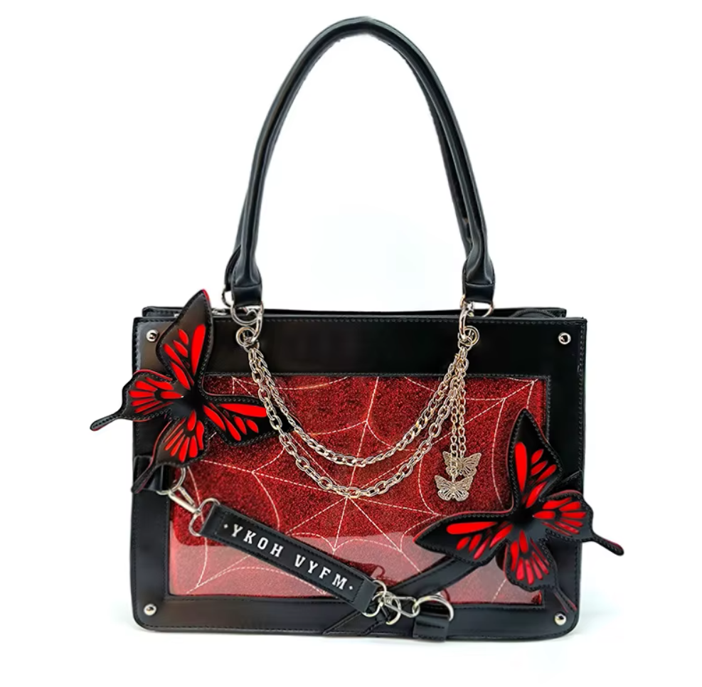 Black leather handbag with a red spiderweb-patterned front panel, silver chain straps, butterfly embellishments, and a black hanging tag with white text.