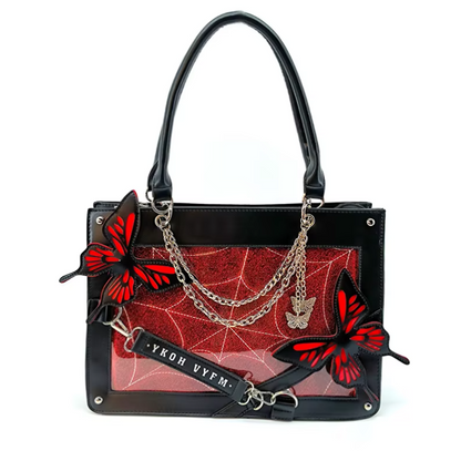 Black leather handbag with a red spiderweb-patterned front panel, silver chain straps, butterfly embellishments, and a black hanging tag with white text.