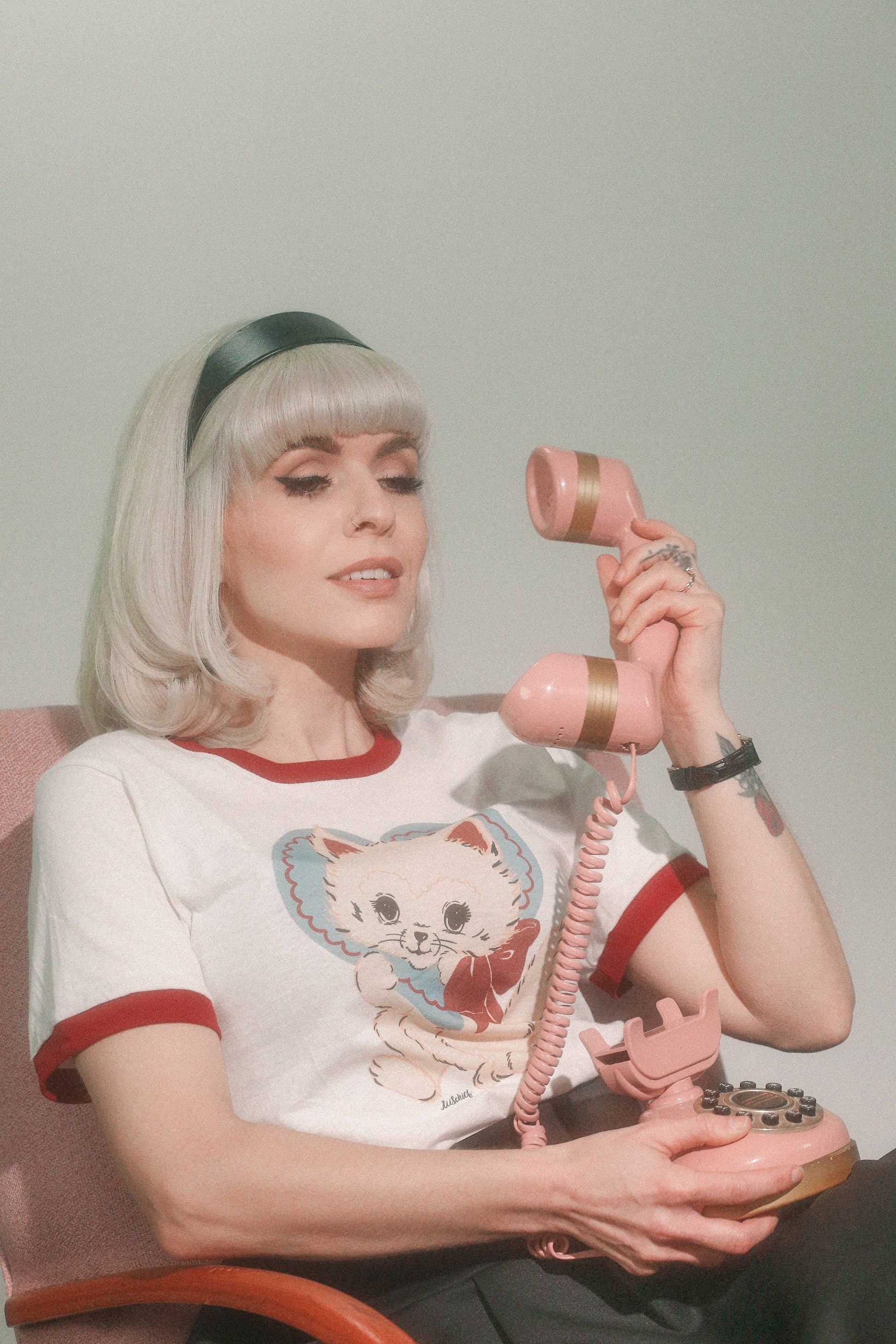 Person holding a pink retro phone with a plain background