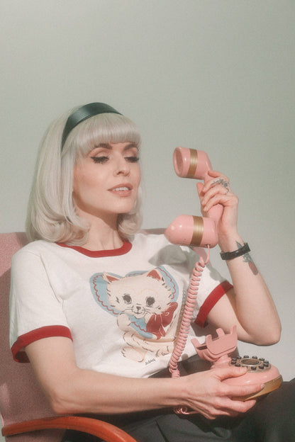 Person holding a pink retro phone with a plain background