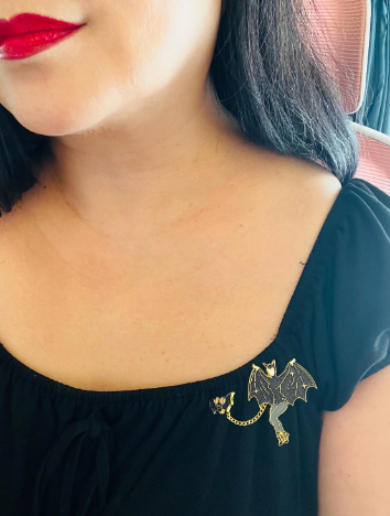 Black top with a dragon brooch worn by a person