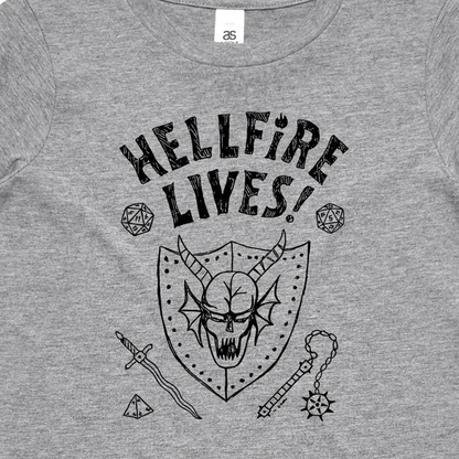 A close-up of a heather gray t-shirt featuring a black graphic print of a horned skull in a shield, surrounded by fantasy-themed icons including dice, a sword, and a mace, with the text 'HELLFIRE LIVES!'.
