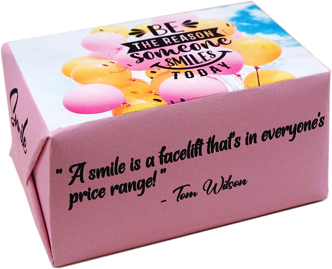 A pink gift box with printed quotes and balloon graphics, photographed on a white background.
