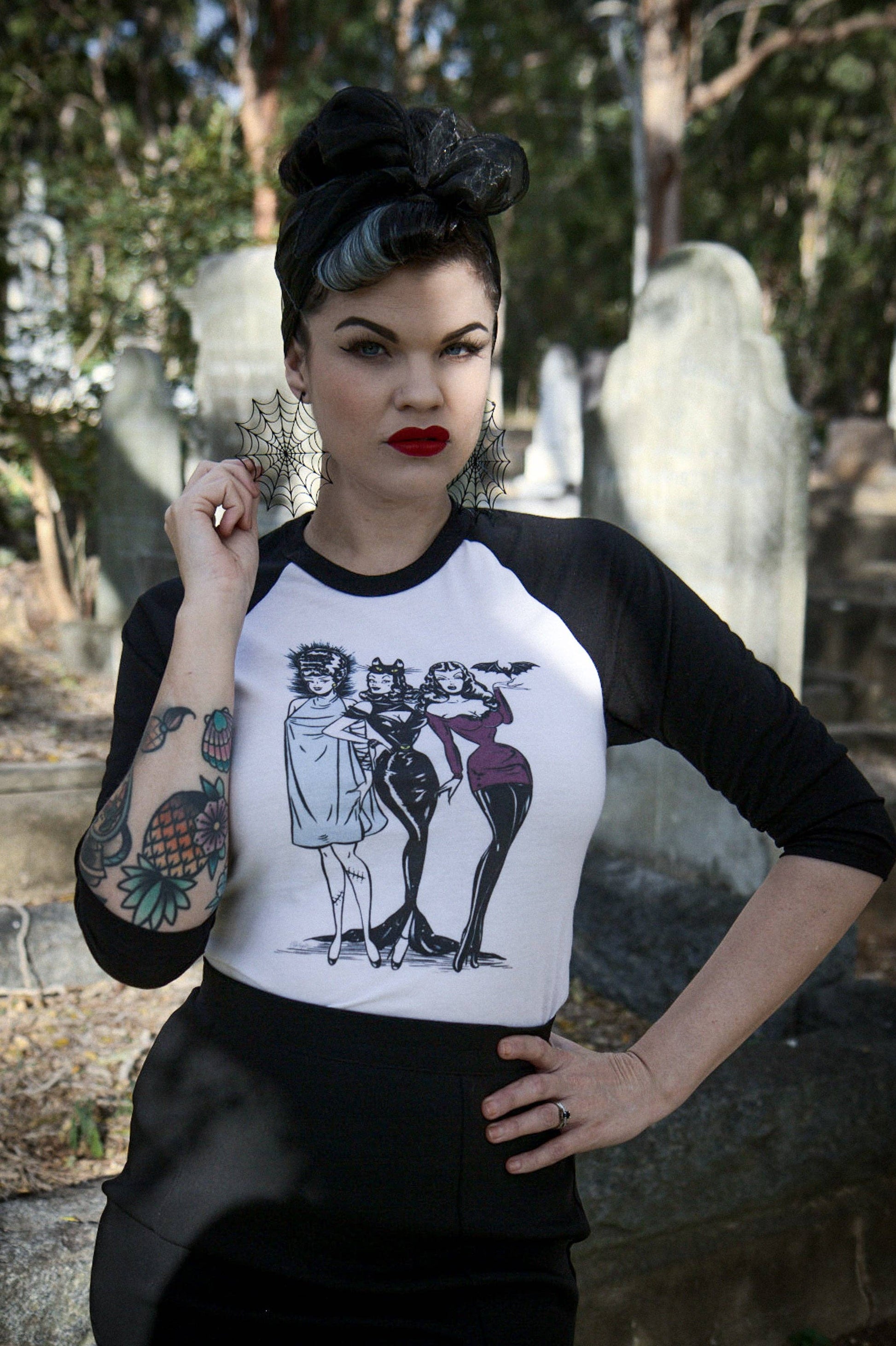 Woman wearing a black and white baseball shirt with graphic design in a cemetery.