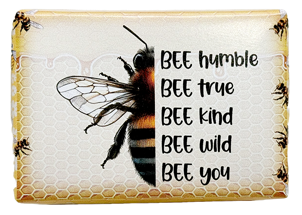 A rectangular decorative plaque or sign featuring a large honeybee illustration over a honeycomb pattern, with the phrase 'BEE humble BEE true BEE kind BEE wild BEE you' printed in black text on the right. The design has a warm beige and yellow background with small bee motifs along the border.