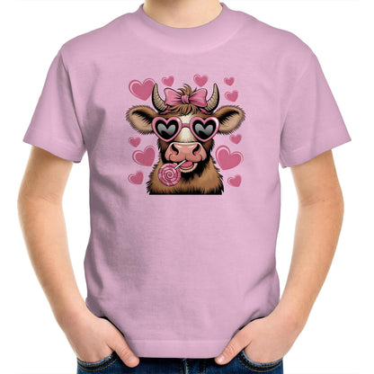 A pink youth t-shirt with a graphic print of a highland cow wearing sunglasses and licking a lollipop, surrounded by heart shapes.