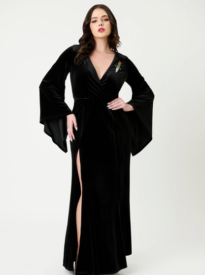 Woman wearing a black evening gown with a high slit on a white background