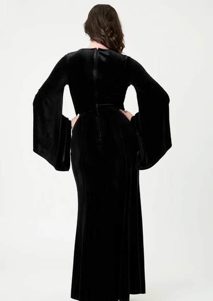 Person wearing a black velvet dress with wide sleeves on a white background