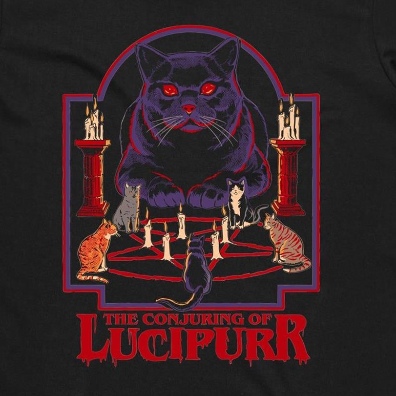 A black graphic print featuring a large purple cat with glowing red eyes sitting above a pentagram and candles, with smaller cats around it and the text 'THE CONJURING OF LUCIPURR' in red at the bottom.