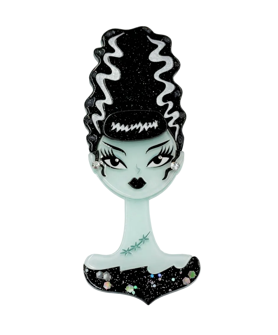 A gothic-style decorative mirror shaped like a woman's bust with black glittery hair, pale mint-green skin, and a black base with small multicolor rhinestone accents, shown on a plain white background.