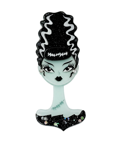 A gothic-style decorative mirror shaped like a woman's bust with black glittery hair, pale mint-green skin, and a black base with small multicolor rhinestone accents, shown on a plain white background.