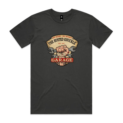 A graphic print on a dark charcoal t-shirt featuring a vintage-style sign that reads 'THE BUSTED KNUCKLE GARAGE' with a bandaged hand and crossed wrenches in the center.