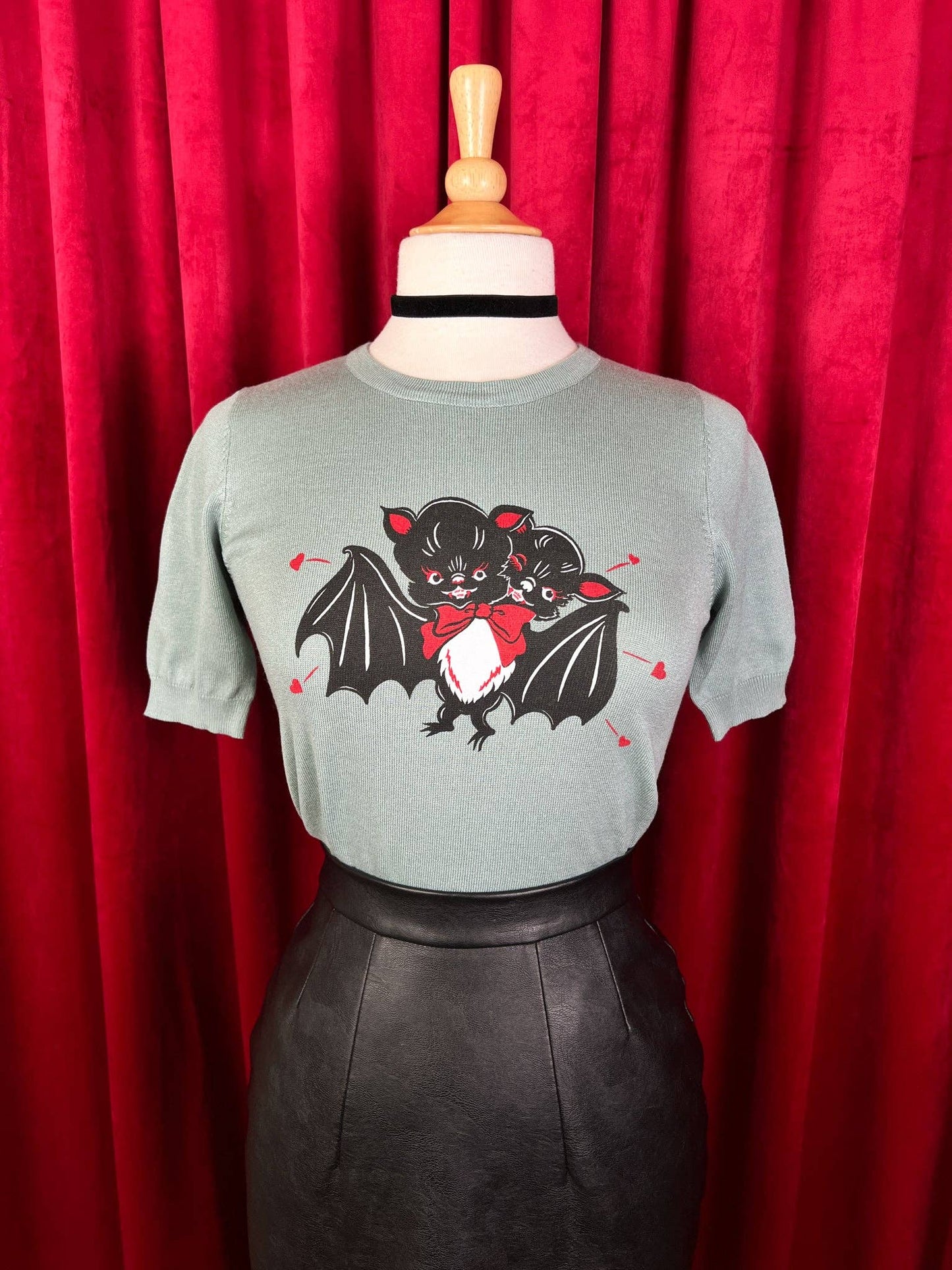 Gray t-shirt with a bat graphic on a mannequin against a red curtain background