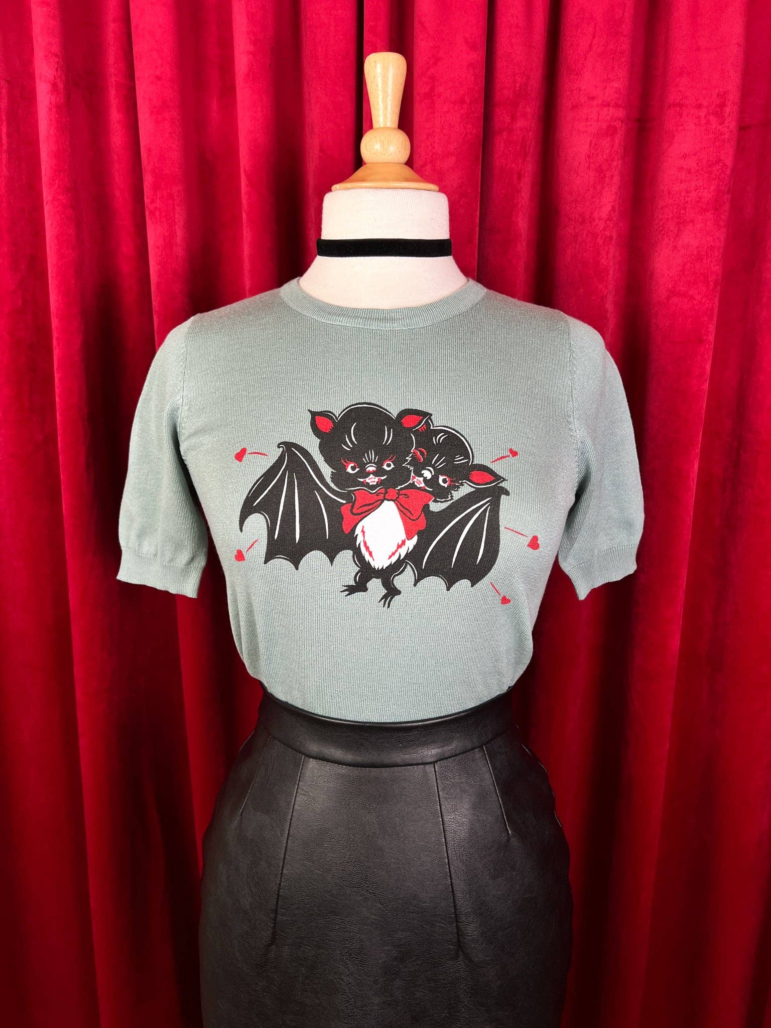 Gray t-shirt with a bat graphic on a mannequin against a red curtain background