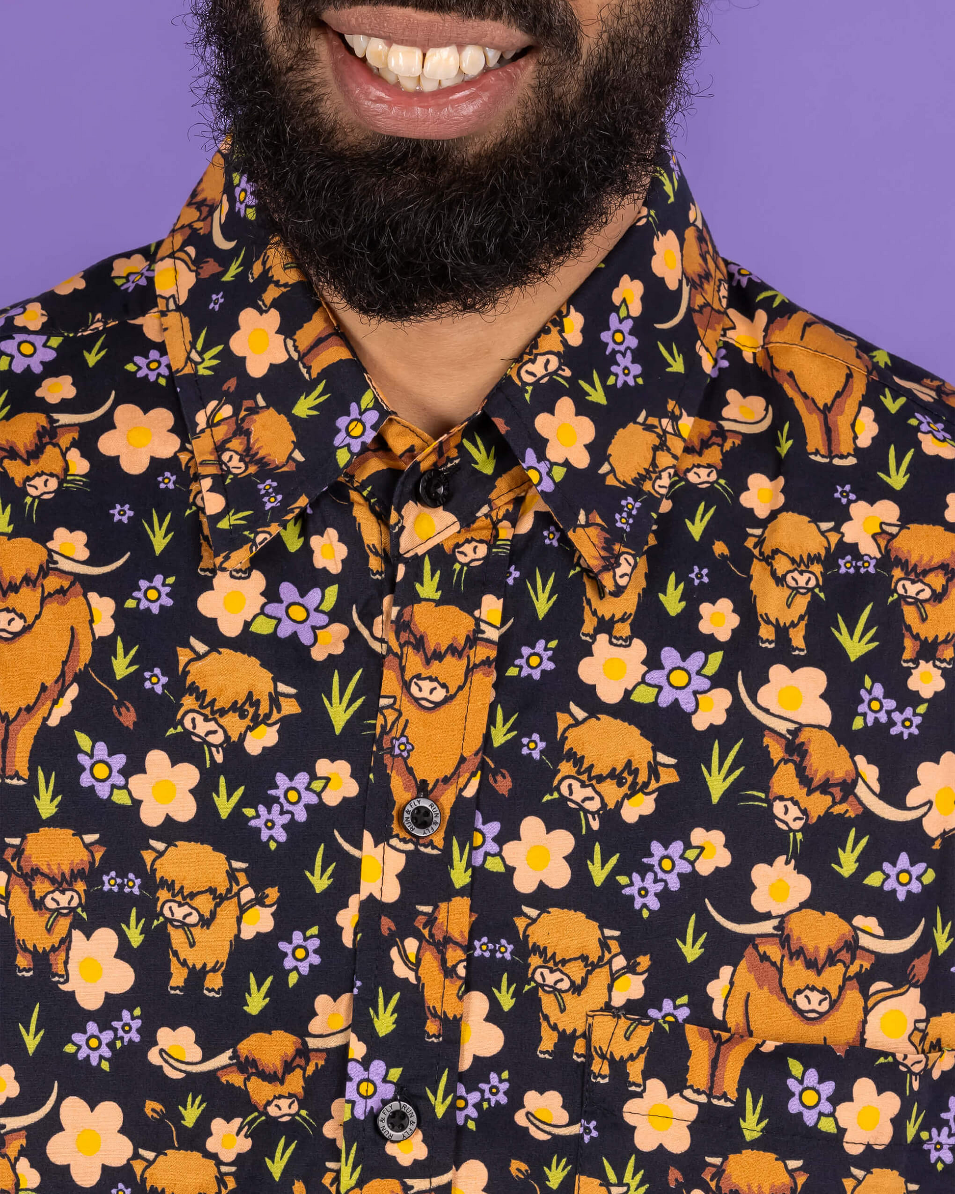 Person wearing a shirt with a pattern of orange animals and flowers on a dark background