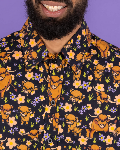 Person wearing a shirt with a pattern of orange animals and flowers on a dark background