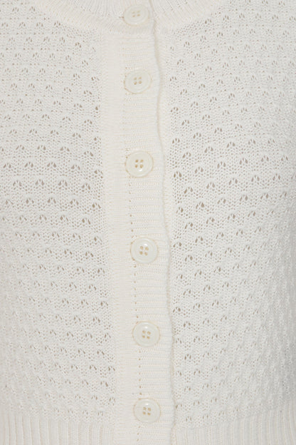 Close-up of a textured white cardigan with button details
