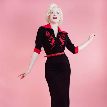 Woman wearing a black dress with red accents against a pink background