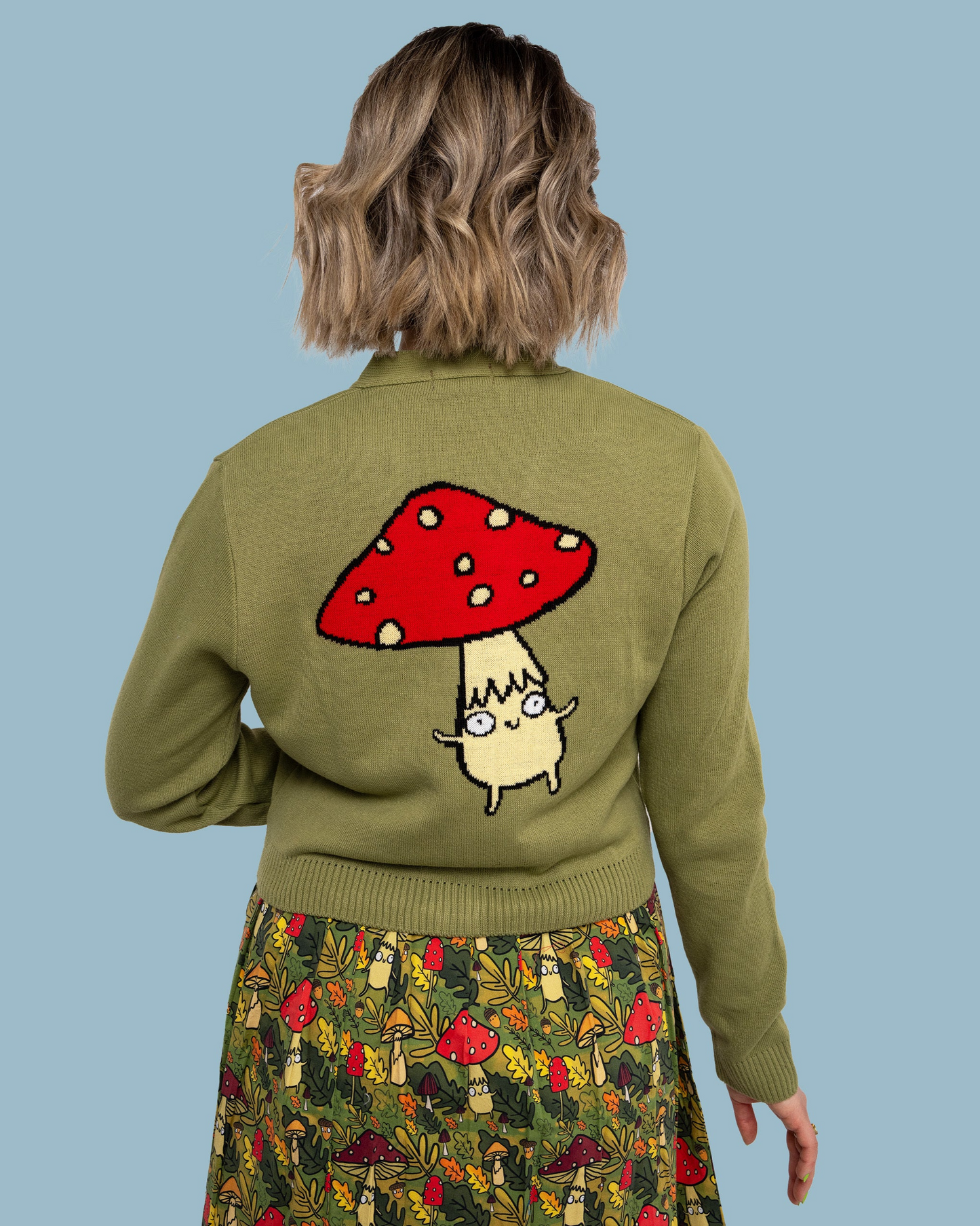 Person wearing a green sweater with a mushroom design on a blue background