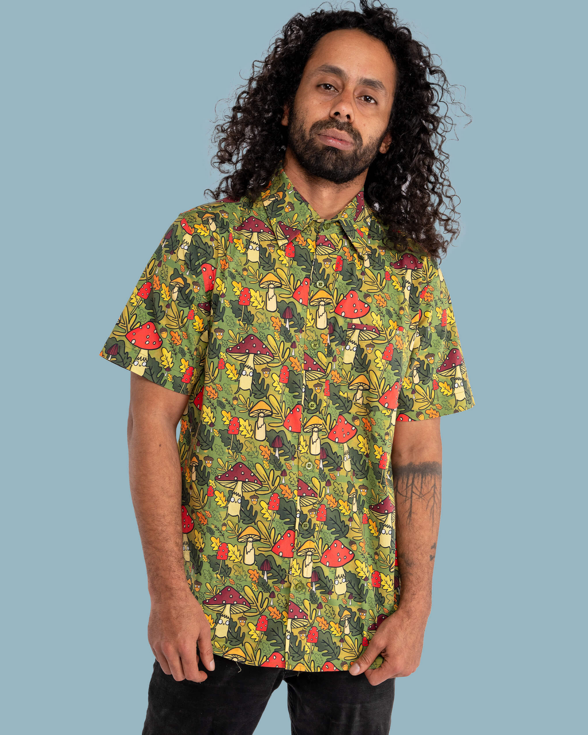 Man wearing a colorful mushroom-patterned shirt against a blue background