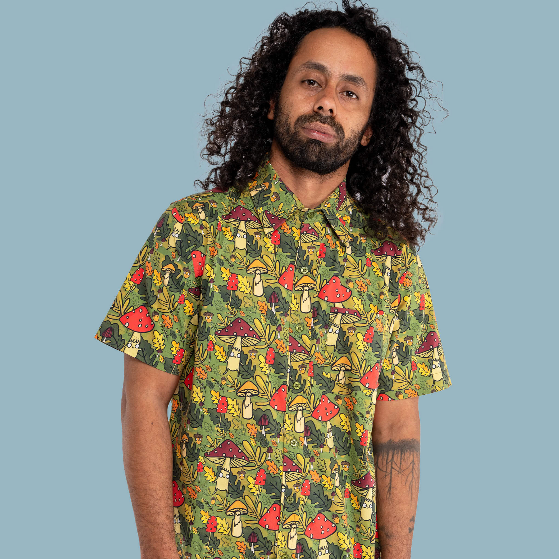 Man wearing a colorful mushroom pattern shirt against a blue background