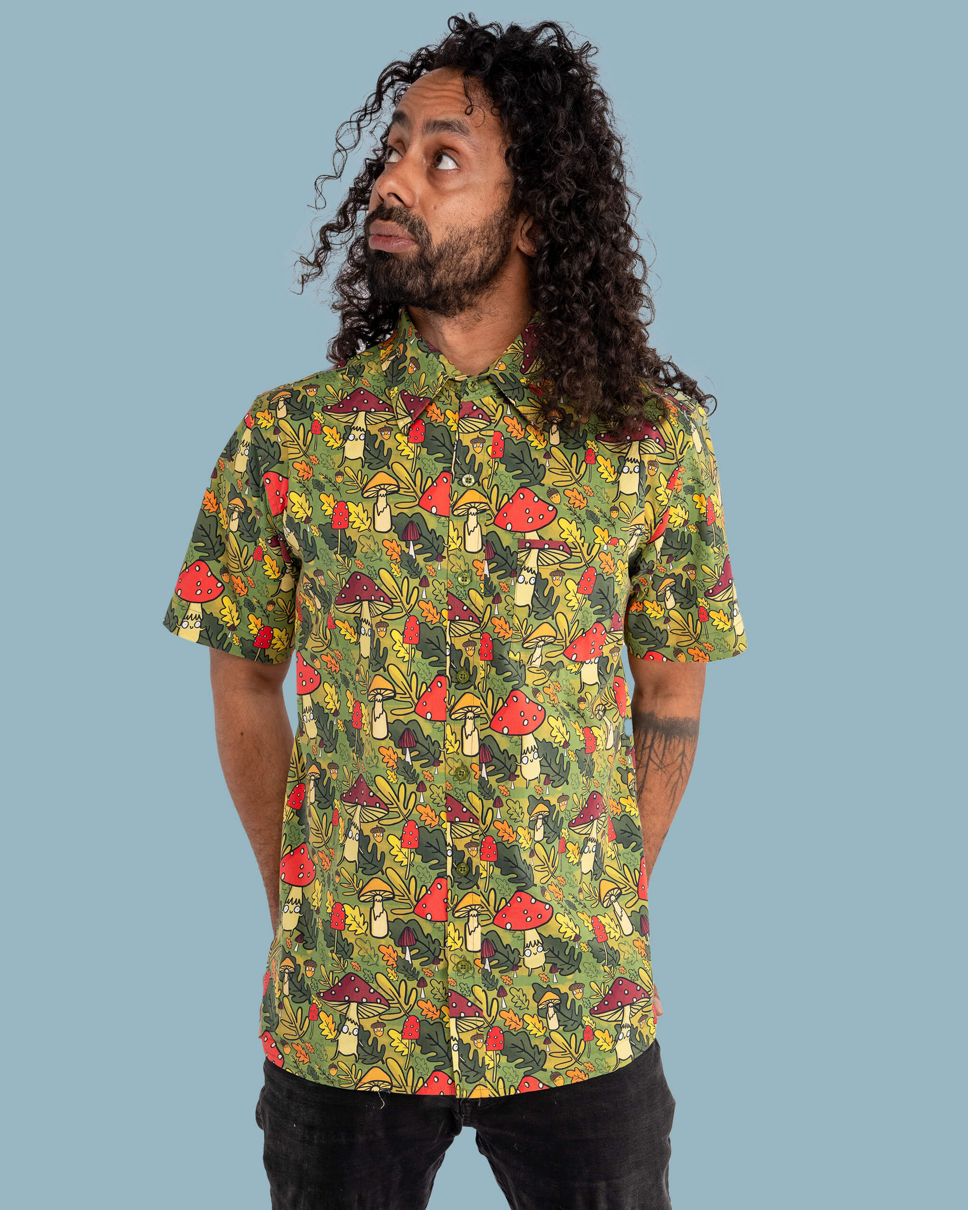 Man wearing a colorful mushroom pattern shirt against a blue background