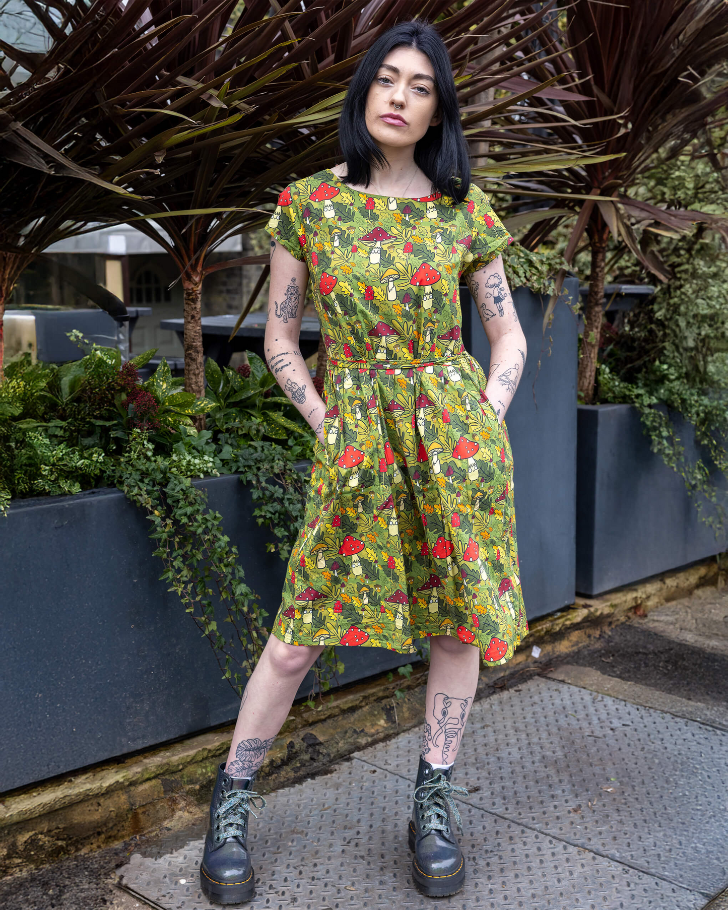 Person wearing a floral dress standing outdoors with plants in the background