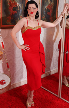 Woman in a red dress with gold accents standing in front of a mirror.