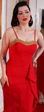 Woman wearing a red dress with gold trim indoors.