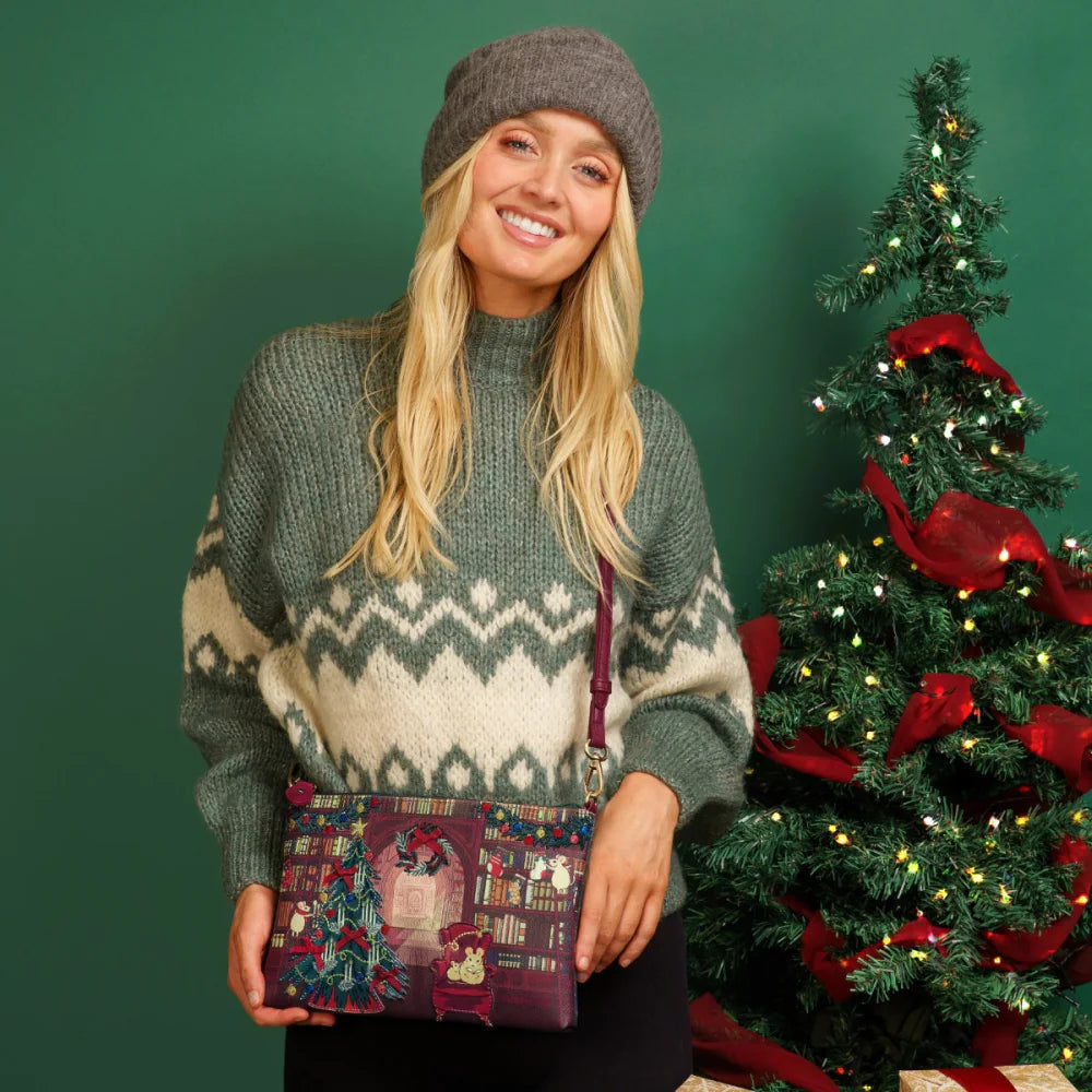 Woman in a patterned sweater holding a festive bag with a Christmas tree in the background