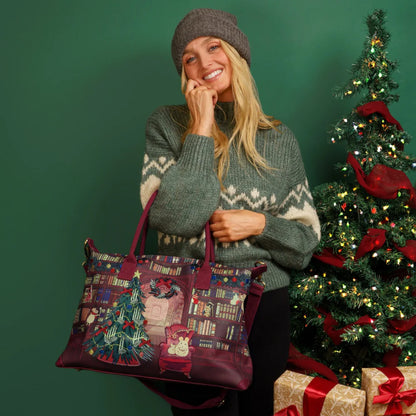 Woman holding a Christmas-themed bag in front of a decorated tree and presents.